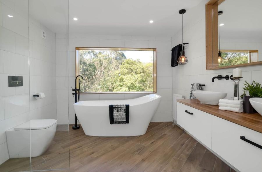 Modern white bathroom with freestanding bath, timber vanity and black tapware