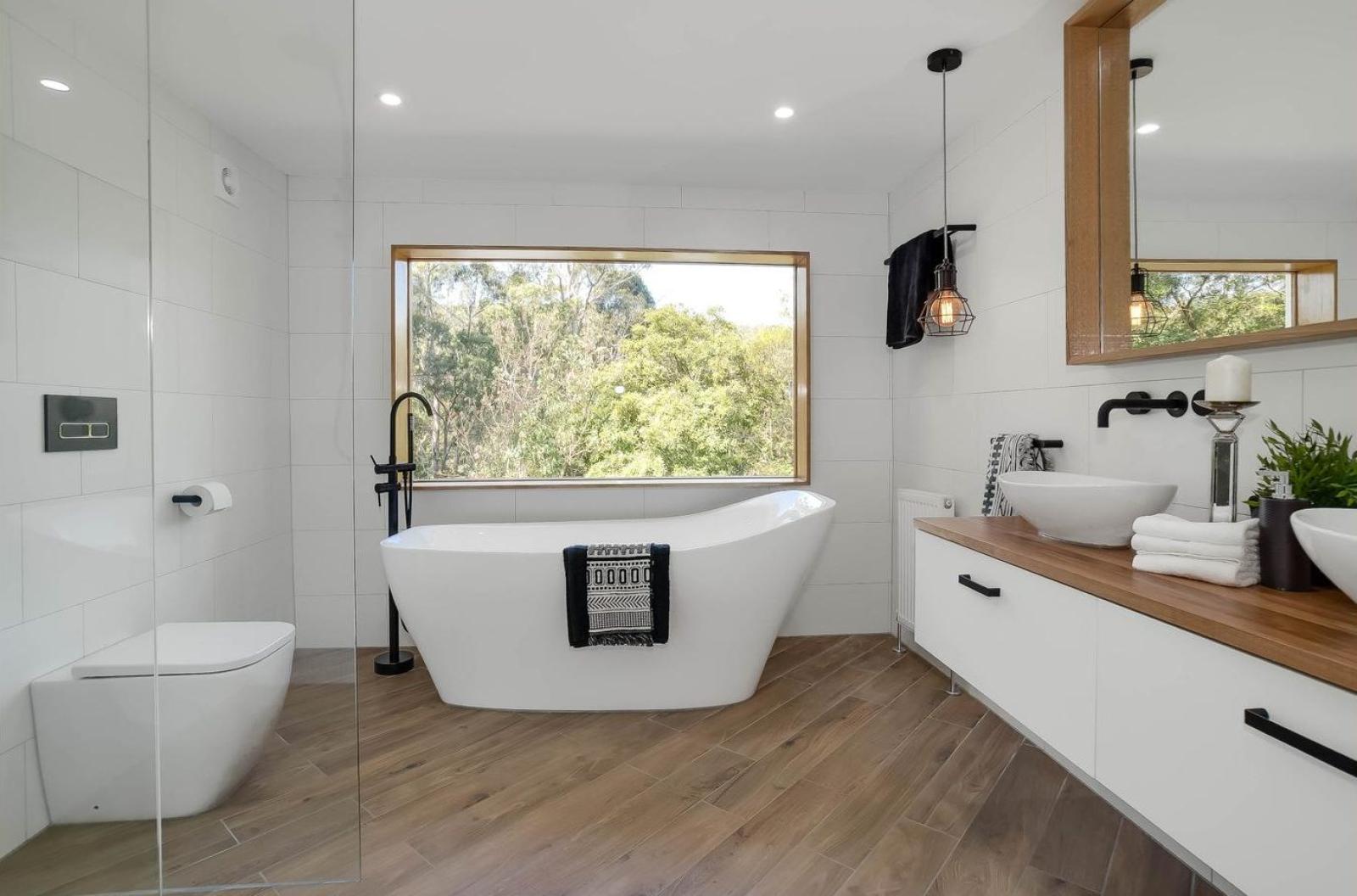 Modern white bathroom with freestanding bath, timber vanity and black tapware