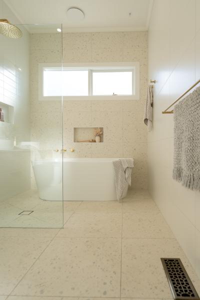 Bright white bathroom with freestanding bath, terrazzo floor tiles and walk-in shower
