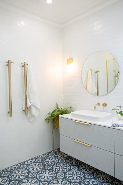 Modern white bathroom with patterned floor tiles, round mirror and floating vanity