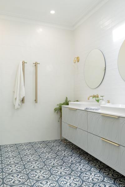 Bright white bathroom with patterned floor tiles, floating vanity and round mirror