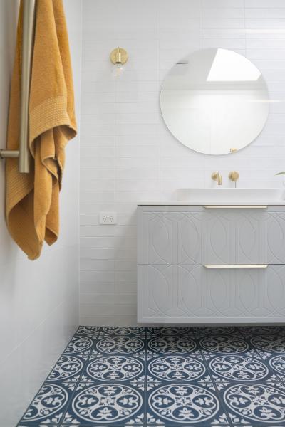 Modern white bathroom vanity with round mirror and patterned floor tiles