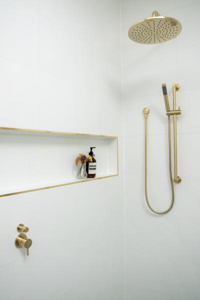 Walk-in shower with brushed brass fittings and recessed shower niche
