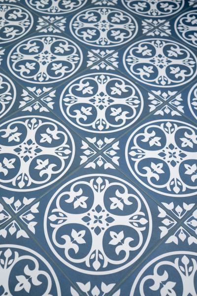 Blue and white patterned encaustic-style floor tiles in a repeating geometric floral design