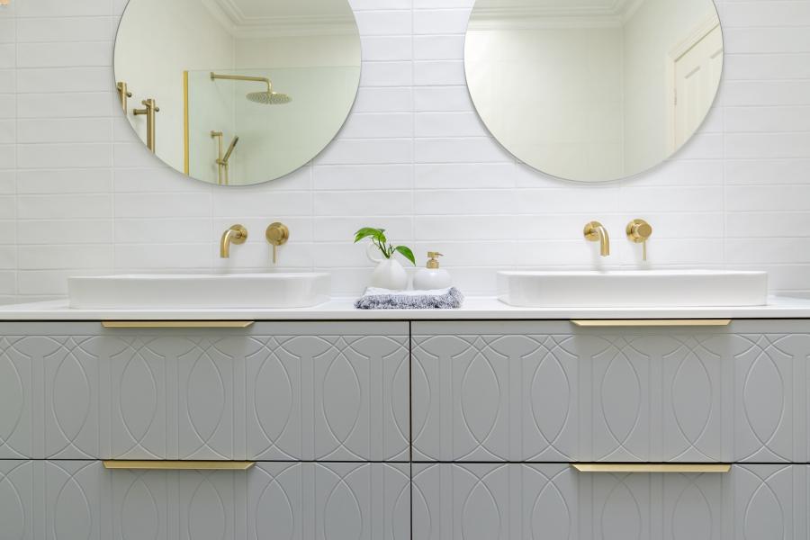 Double vanity bathroom with round mirrors, white basins and brushed brass tapware