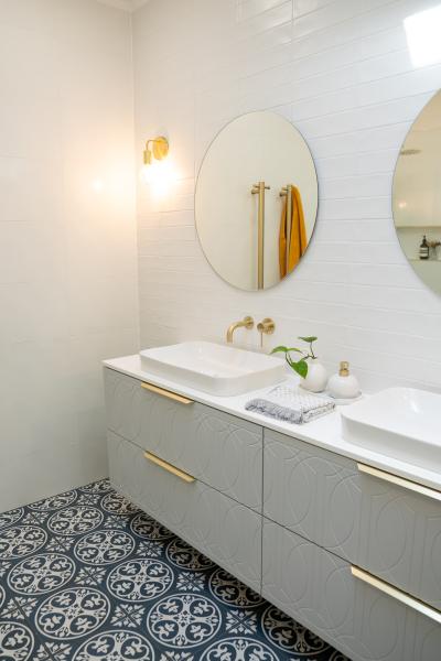 Modern bathroom vanity with oval mirrors, white basins and patterned floor tiles