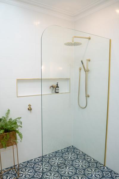 Walk-in shower with niche shelf, brass fittings and patterned floor tiles