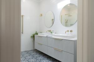 Modern bathroom with double vanity, brass tapware, and patterned floor tiles