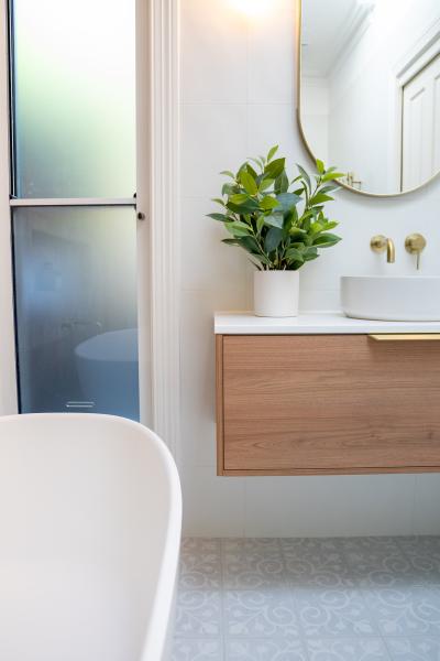 Bright bathroom with freestanding bath, timber vanity, round mirror and frosted glass shower screen