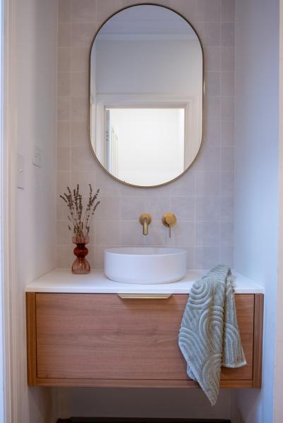 Modern bathroom vanity with oval mirror, vessel basin and timber cabinetry