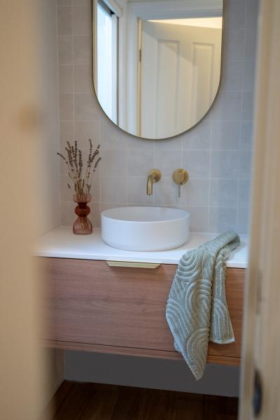 Modern bathroom vanity with round basin, mirror and brass tapware