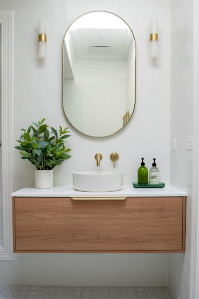 Modern floating timber vanity with oval mirror and vessel basin in a bright white bathroom