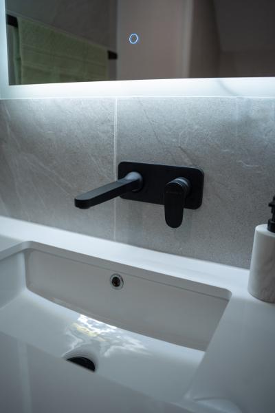 Modern bathroom vanity with wall-mounted black tapware, mirror and white basin