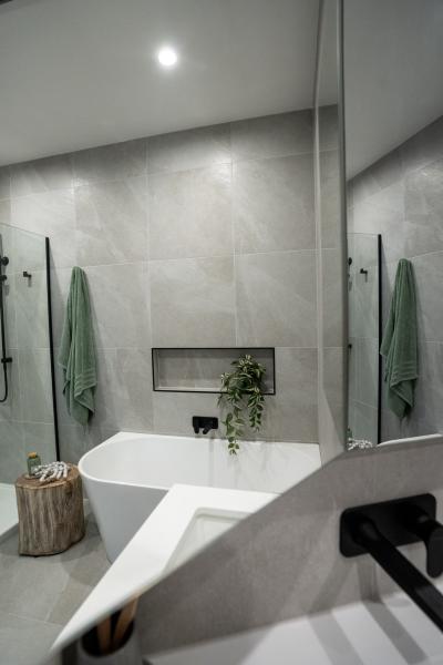 Modern bathroom with freestanding bath, wall niche and black tapware