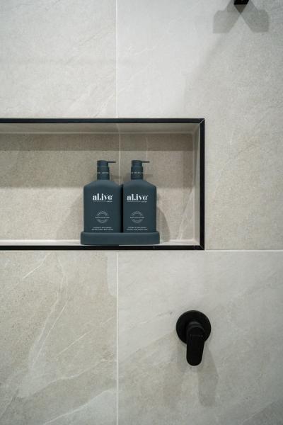 Recessed shower niche with black tapware in a beige tiled bathroom wall