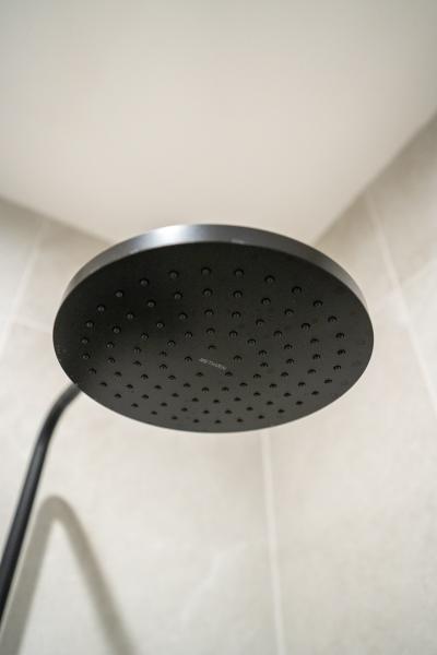 Matte black round rainfall shower head in a tiled bathroom