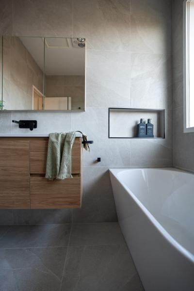 Modern bathroom with floating timber vanity, built-in bath and tiled wall niche