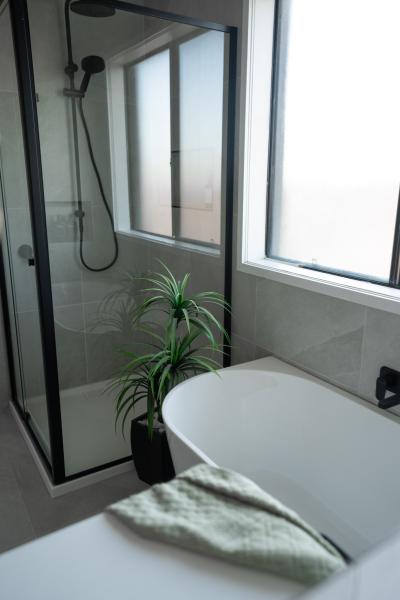Modern bathroom with freestanding bath, black-framed shower and frosted window