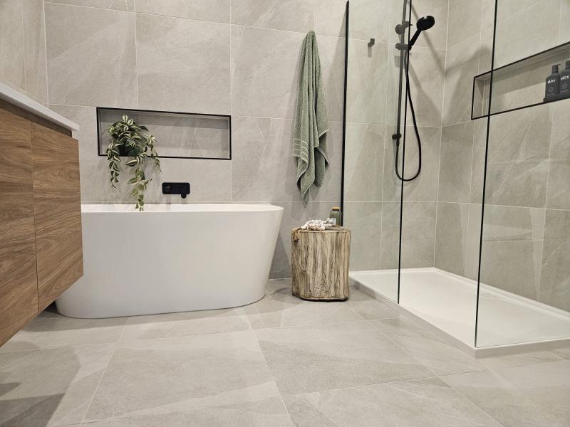Modern bathroom with freestanding bath, walk-in shower, timber vanity and light stone-look tiles