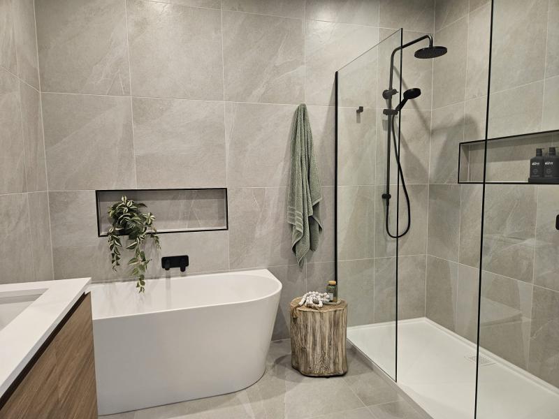 Modern bathroom with freestanding bath, walk-in shower and grey wall tiles