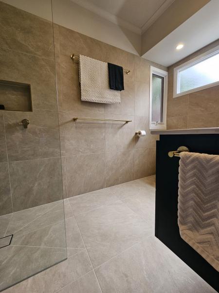 Modern bathroom with walk-in shower, towel rail, floating vanity and frosted window