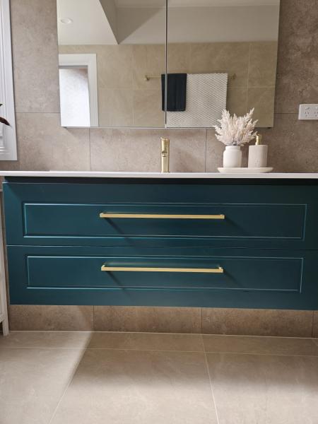 Teal floating bathroom vanity with brass handles beneath a mirrored wall cabinet
