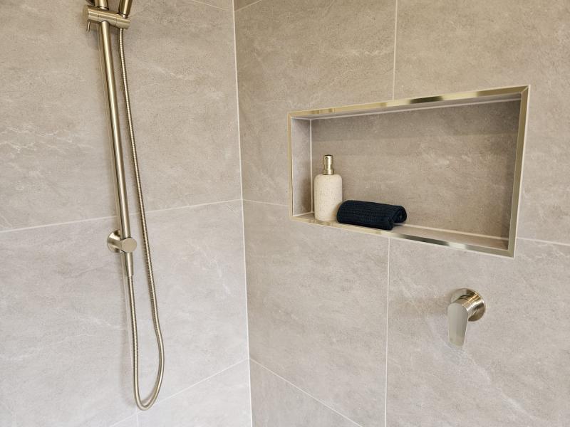 Modern tiled shower with wall niche, handheld shower rail and neutral stone-look tiles
