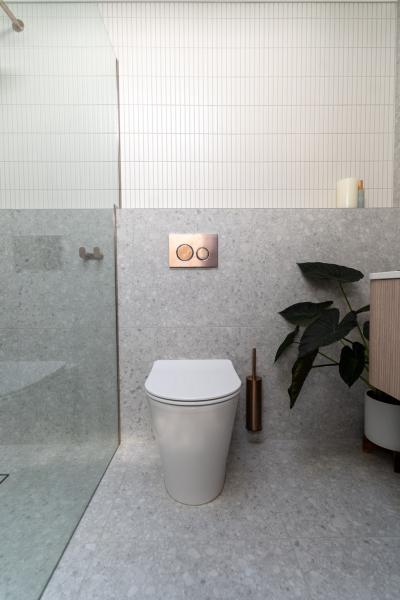 Modern bathroom with wall-hung toilet, glass shower screen and white vertical tiles