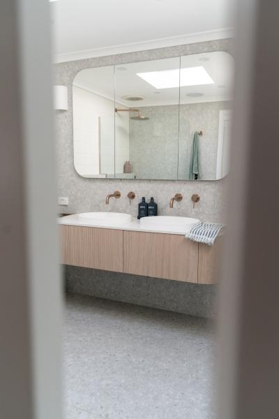 Modern bathroom vanity with curved mirror, twin basins and brushed brass tapware
