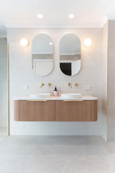 Contemporary bathroom vanity with twin basins, arched mirrors and brass tapware