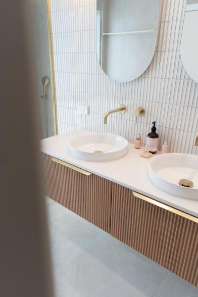 Modern double vanity bathroom with vessel basins, brass tapware and vertical ribbed cabinetry