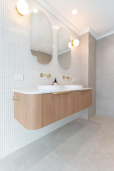 Modern bathroom vanity with twin basins, arched mirrors and vertical white wall tiles