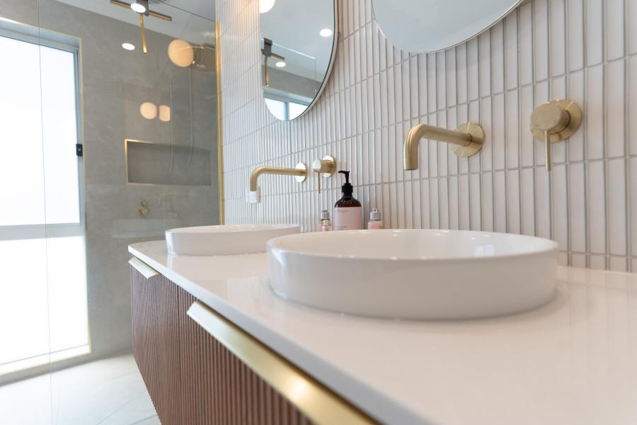 Modern bathroom vanity with white basin, brass tapware and vertical wall tiles