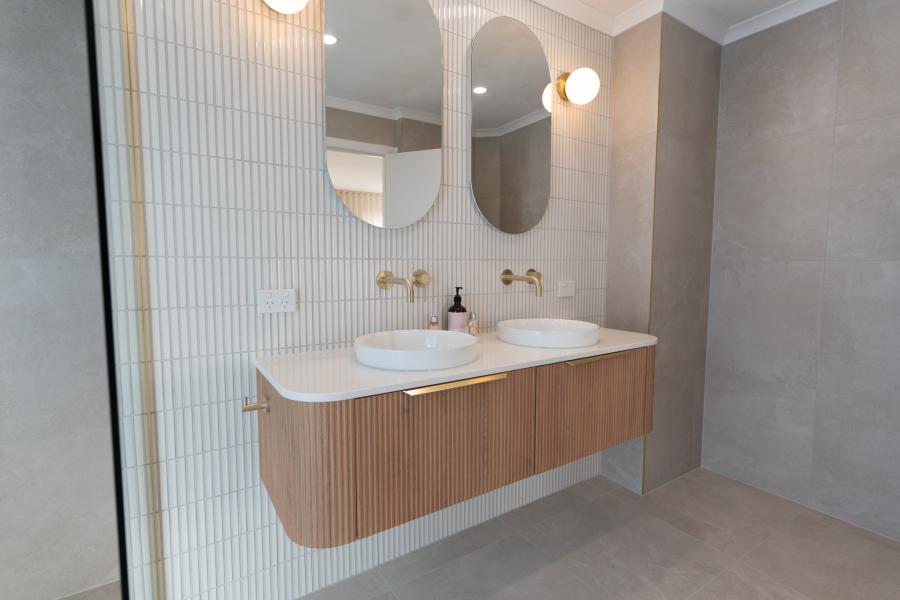 Modern bathroom vanity with double basins, timber cabinetry and curved mirrors