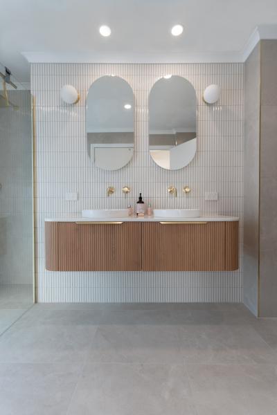 Modern bathroom vanity with double basins, arched mirrors and timber cabinetry