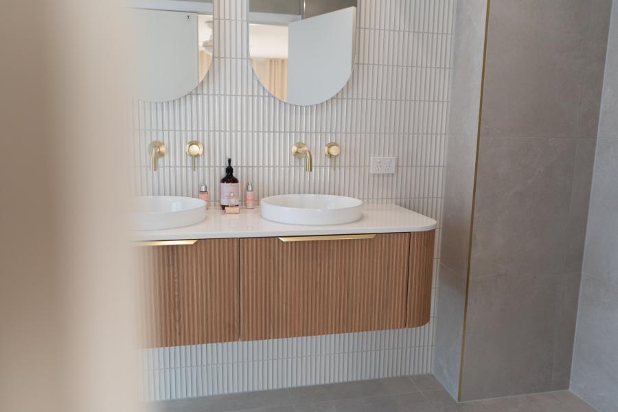 Modern bathroom vanity with twin basins, fluted cabinetry and brass wall taps