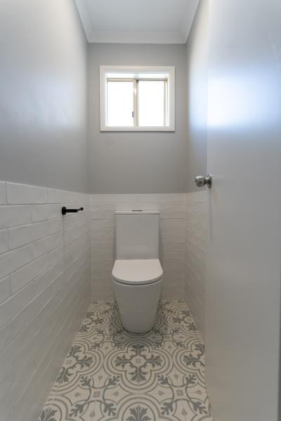 Compact WC with toilet, white wall tiles, grey walls and patterned floor tiles