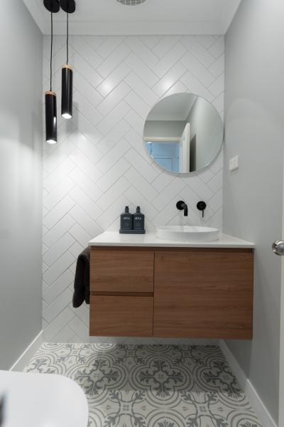 Modern bathroom with timber floating vanity, round mirror and patterned floor tiles