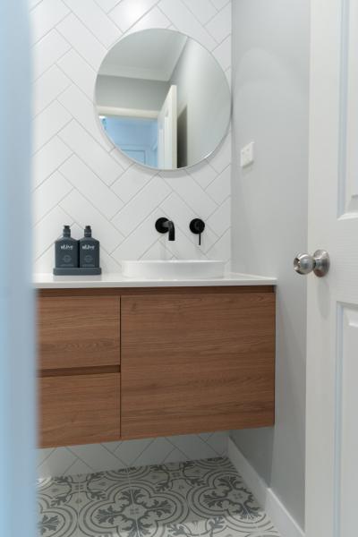 Wall-hung timber vanity with round mirror in a modern bathroom