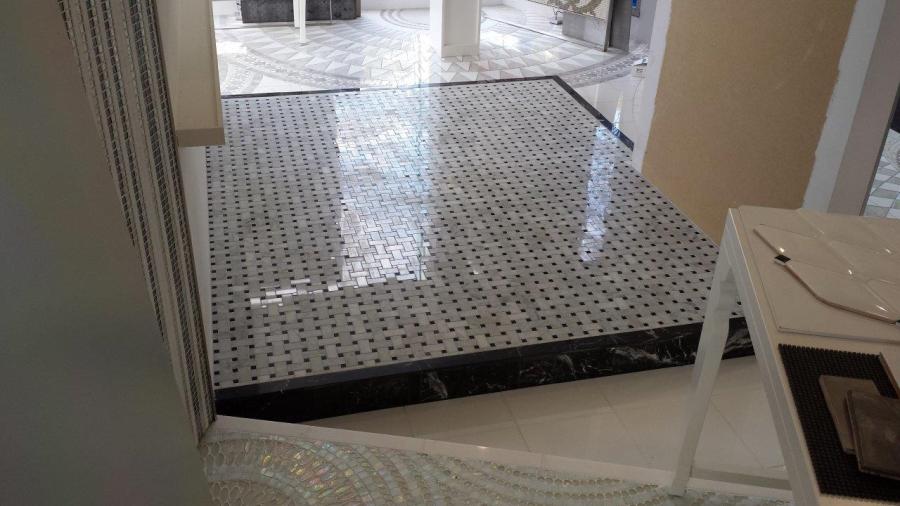 Partially completed tiled bathroom floor with doorway threshold during renovation