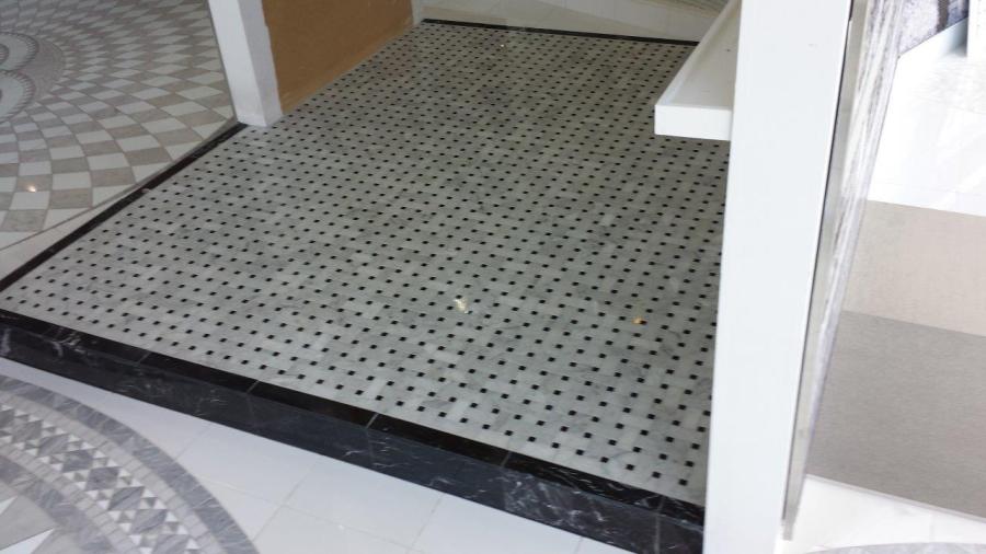 Small tiled shower base with mosaic floor tiles and threshold detail