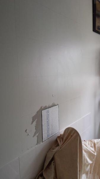 Wall with chipped paint and patching beside a bed during interior repair work