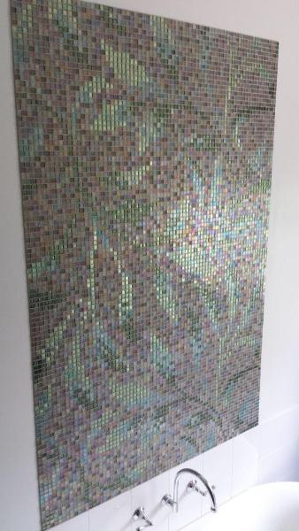 Iridescent mosaic feature wall above a white bath in a modern bathroom