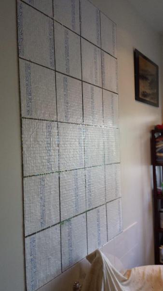 Wall-mounted grid of silver mosaic tile sample boards in an interior showroom