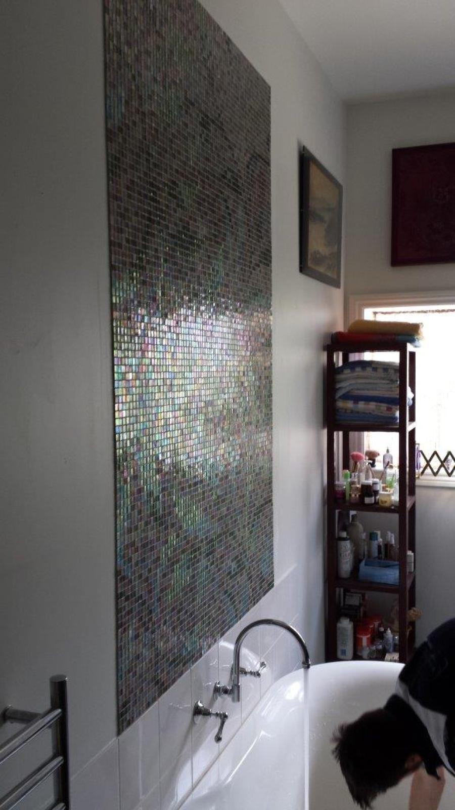 Tall mosaic feature wall above a white bathtub in a modern bathroom