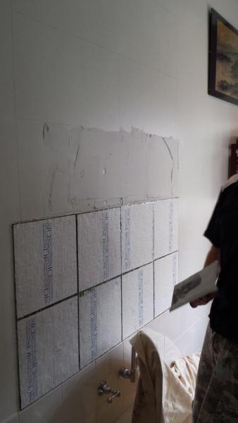 Partly tiled bathroom wall with damaged plaster during renovation work