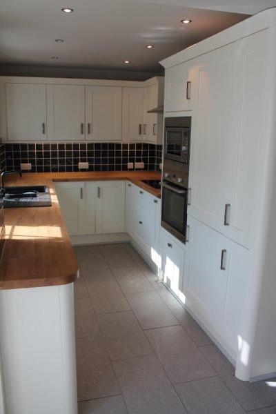 Bright galley kitchen with white cabinetry, timber benchtops and built-in ovens