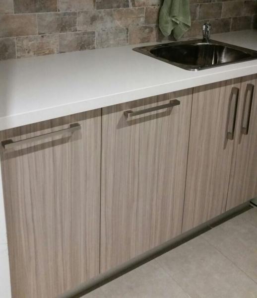 Timber-look laundry cabinetry with white benchtop and inset stainless steel sink