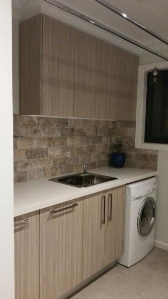 Compact laundry with timber-look cabinetry, benchtop sink and front-load washing machine