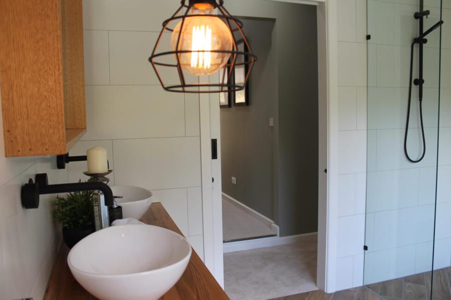 Modern bathroom vanity with vessel basin, timber benchtop and black tapware beside a walk-in shower